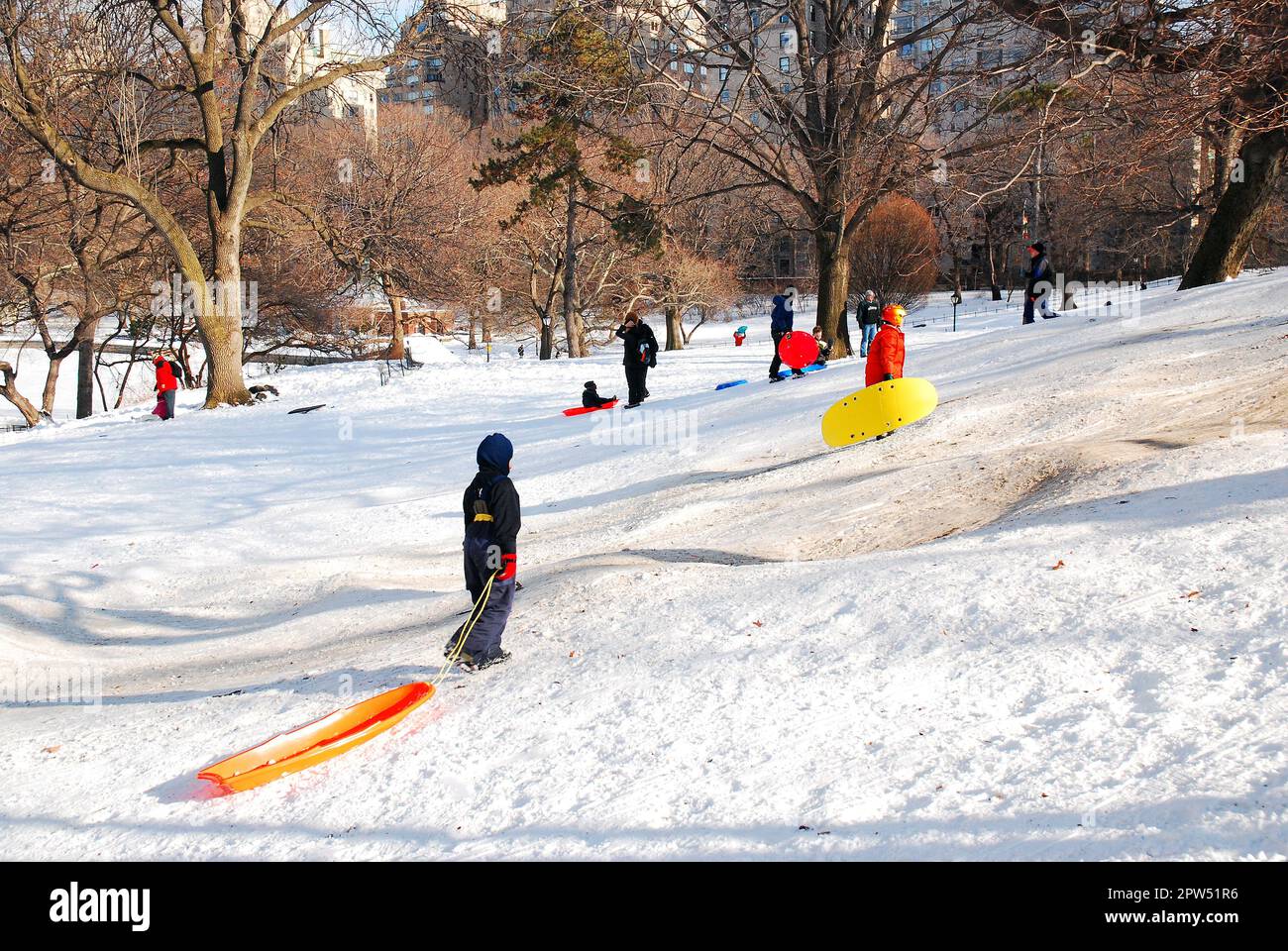 Young children enjoy a winter snow day sledding on a hill in New York's