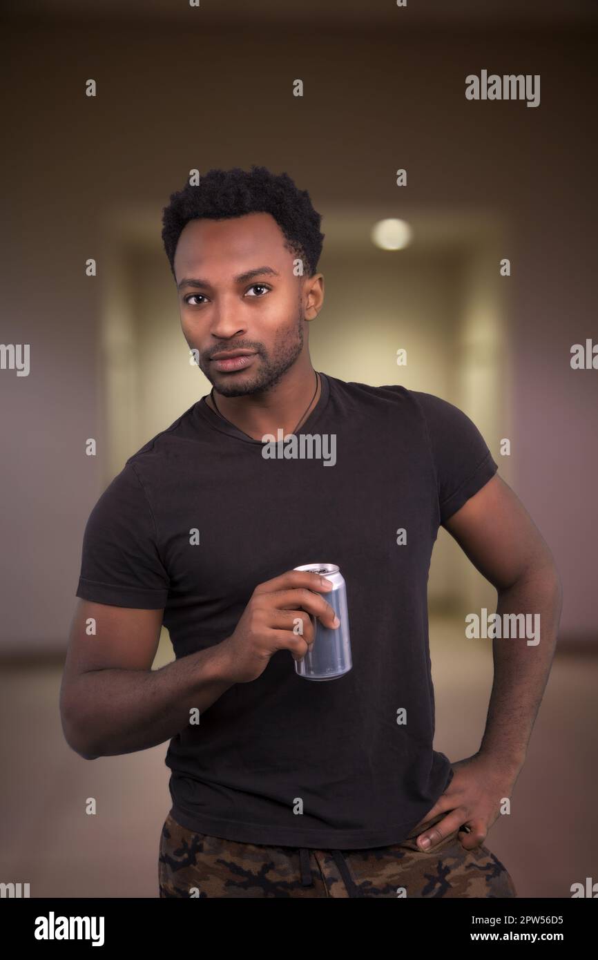 cool attitude man drinking soda holding can cola in hand wearing black t-shirt indoor Stock Photo