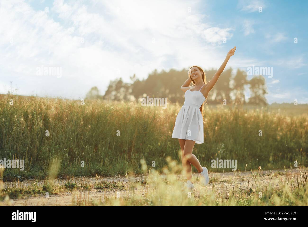 Joyful young woman walking along country road in hot sunny day Stock ...