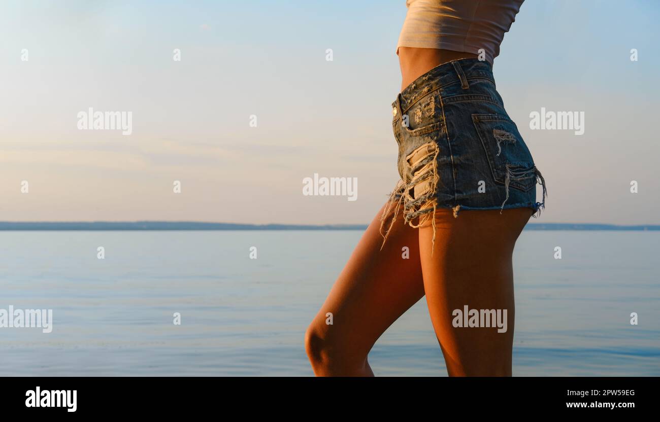 Young slim woman, close-up of tanned stomach, navel, hips, chest, wearing  jeans, lying on towel Stock Photo - Alamy