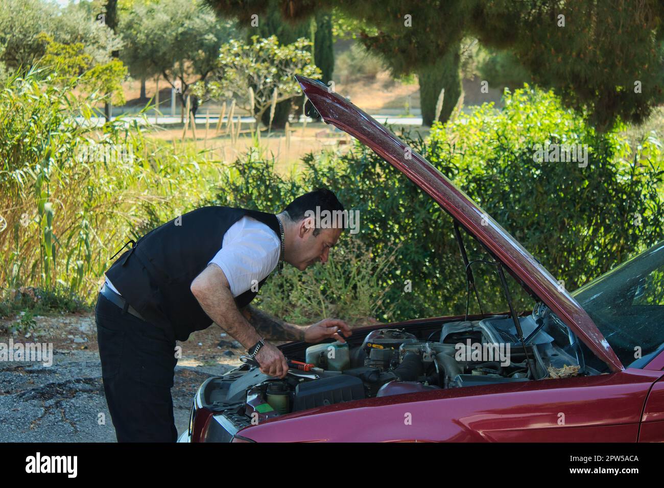 mature man fixing a breakdown in his car engine with tools on the side ...