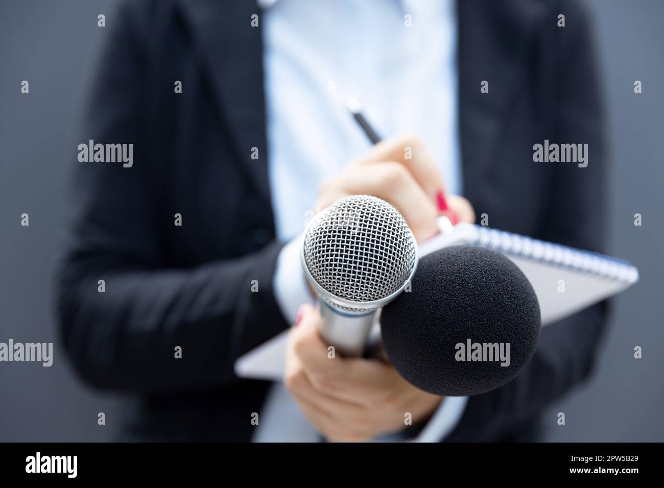 Reporter at press conference or media event, writing notes, holding ...