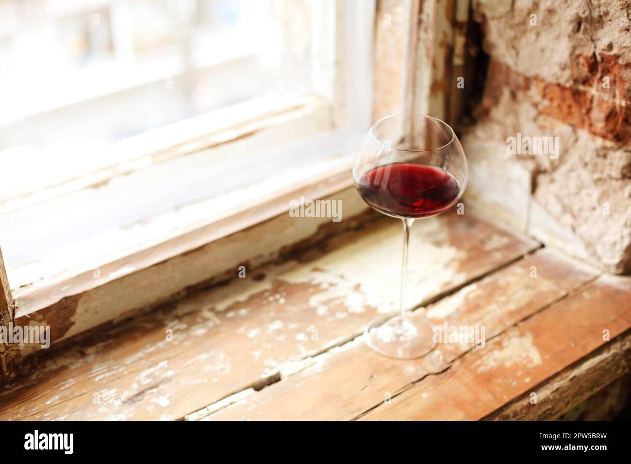 One wineglasse with red wine during party with copy space. Celebration and holiday concept Stock Photo