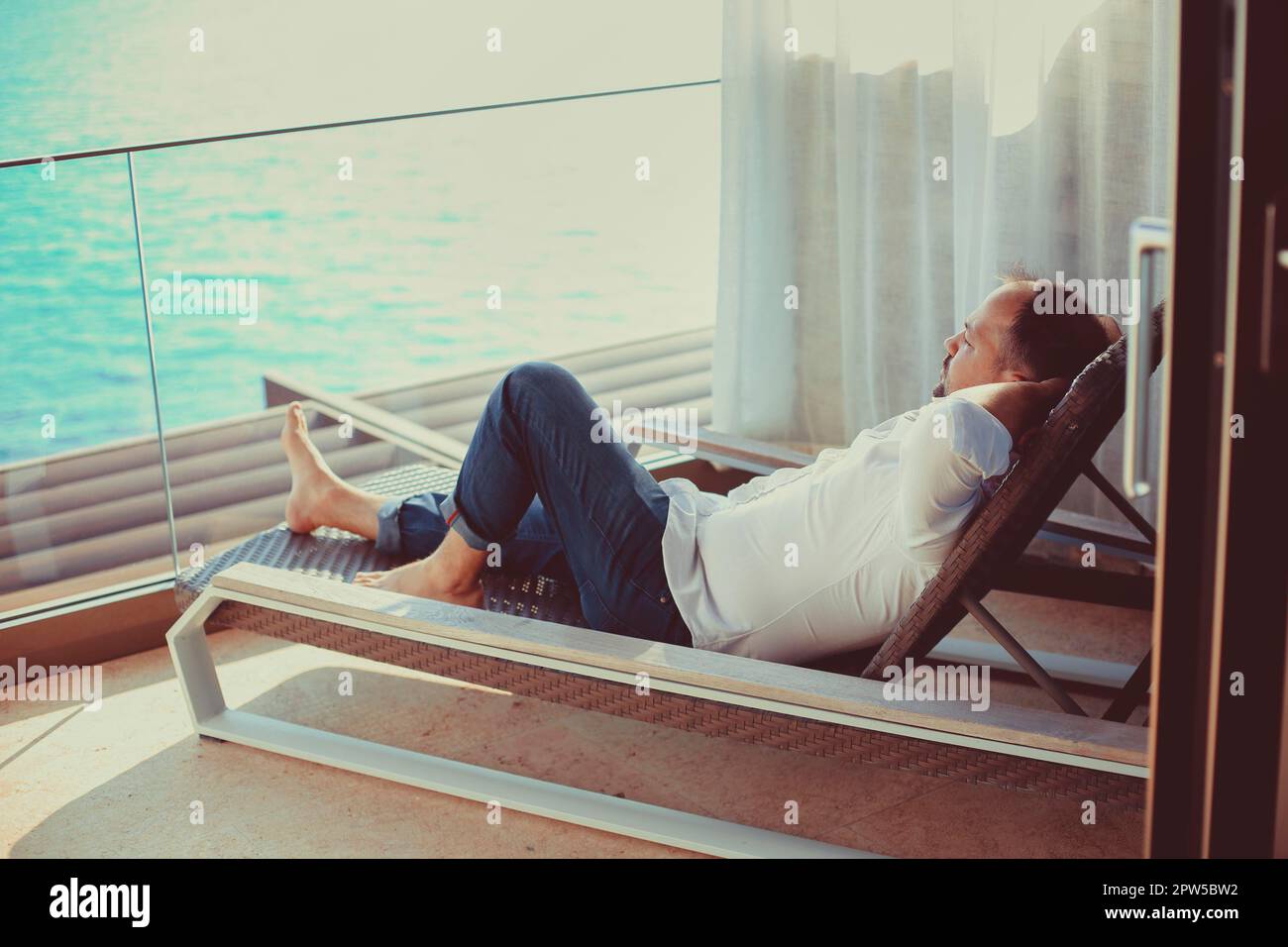 Relaxed young man at home on the balcony. Holiday and travel concept Stock Photo