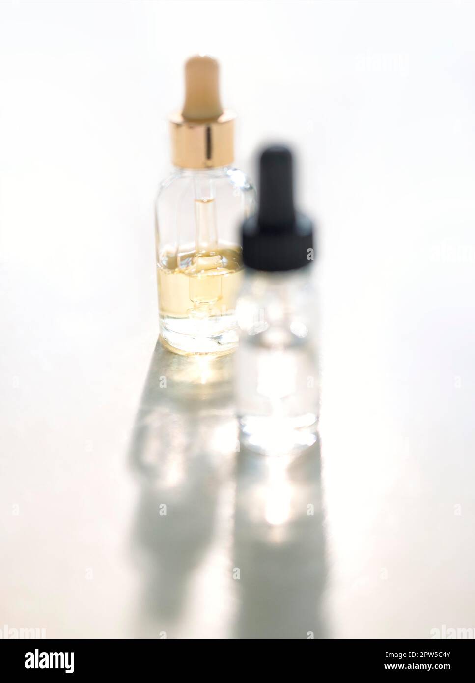 Serum with collagen and peptides in colorful glass bottles on light background with sunlight shadow. Skincare essence for beautiful healthy skin Stock Photo