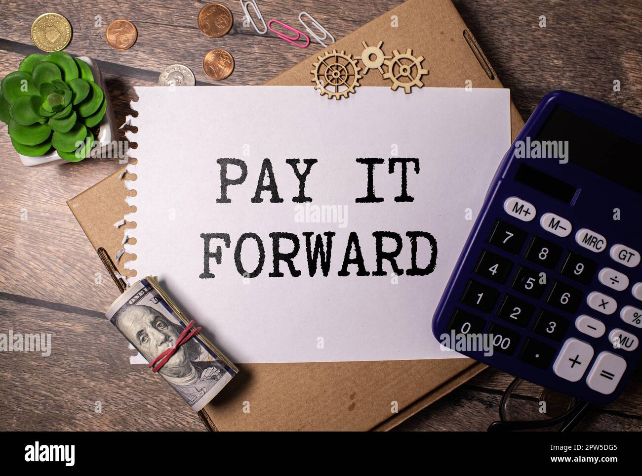 Text PAY IT FORWARD on a notebook with office tools on white background