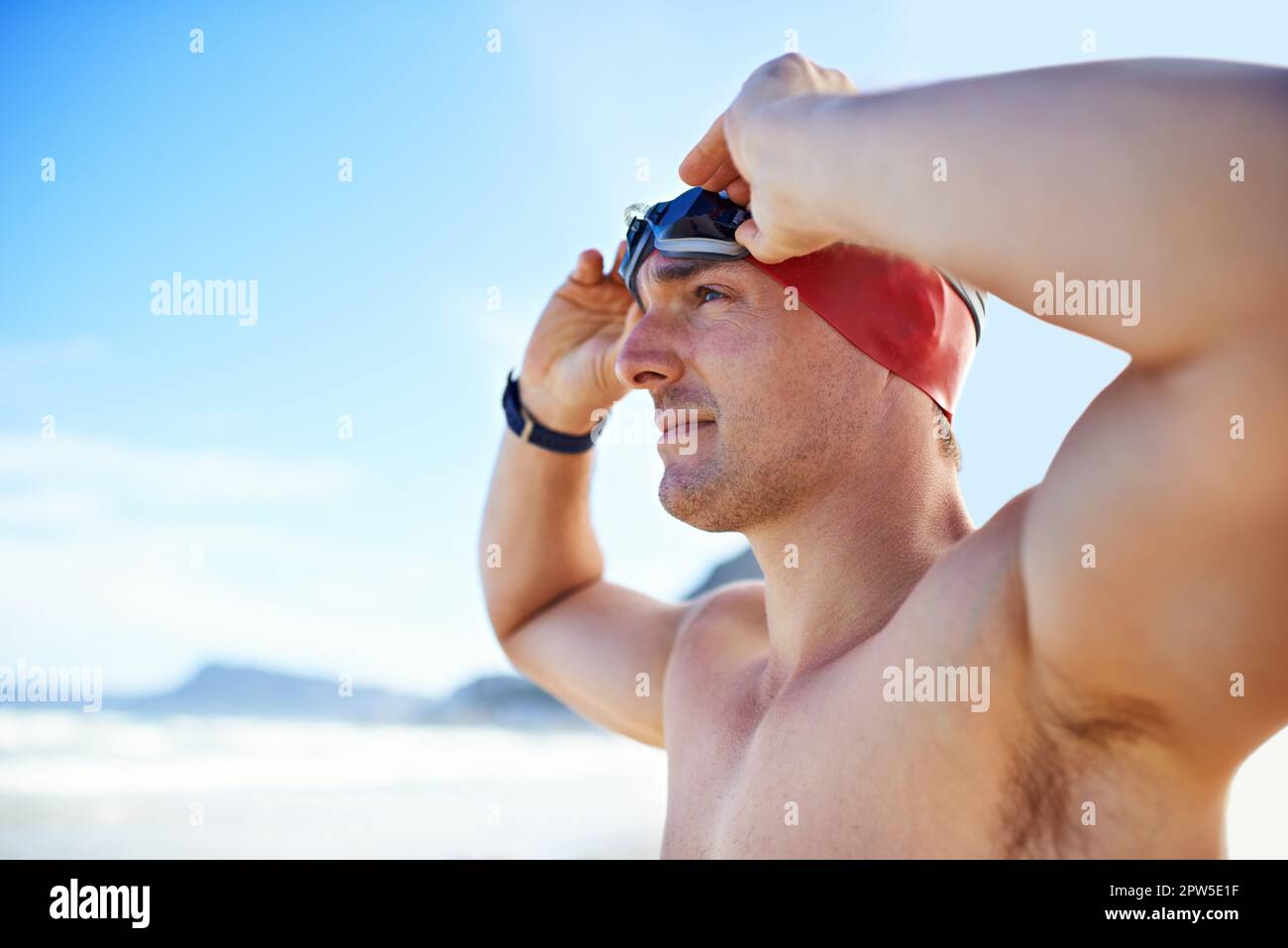 Preparing himself for his own record time. Cropped closeup shot of a man wearing swimming goggles looking out at the ocean Stock Photo