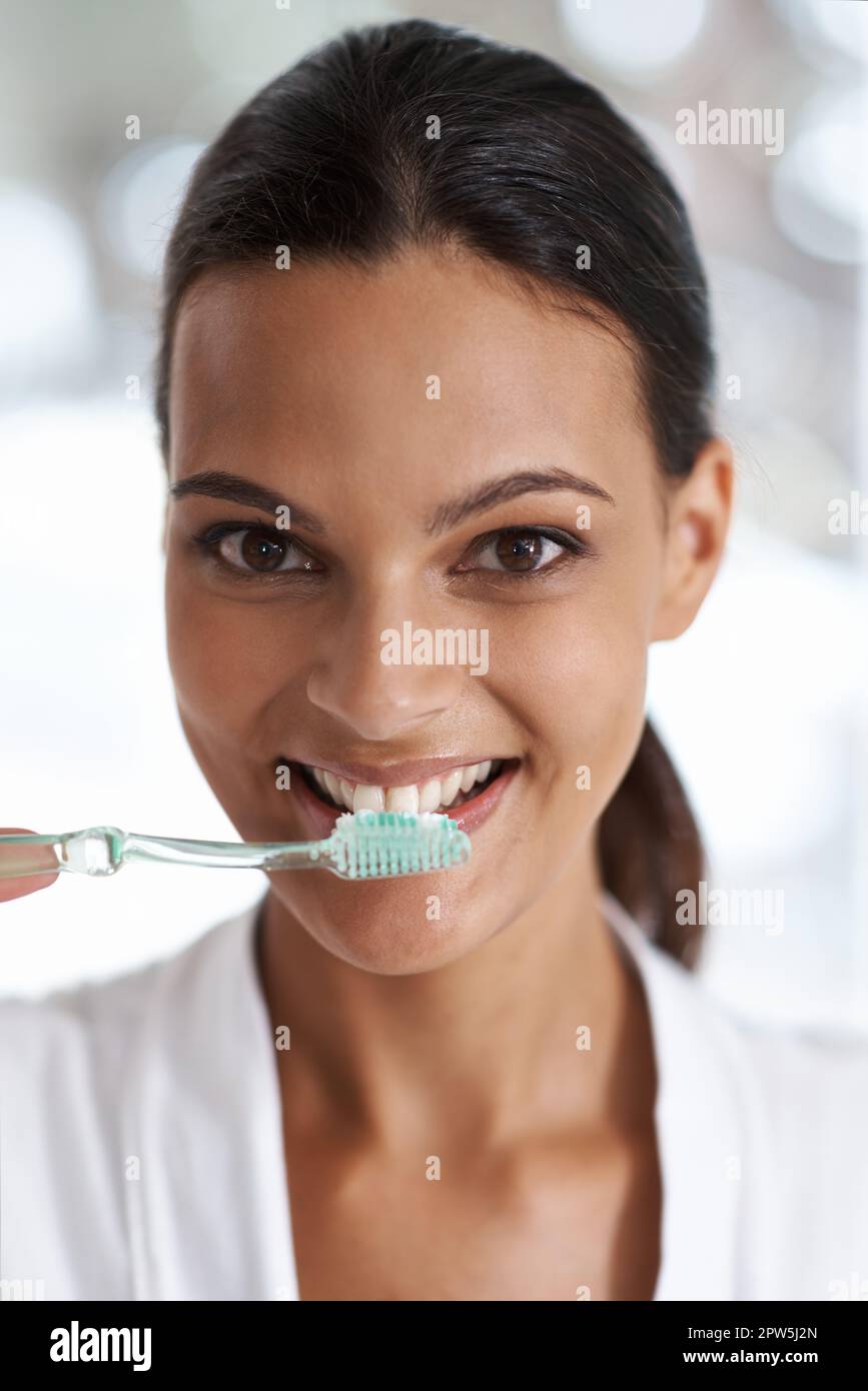 I found the tootphaste the suits me. a smiling young woman brushing her teeth in the mirror Stock Photo