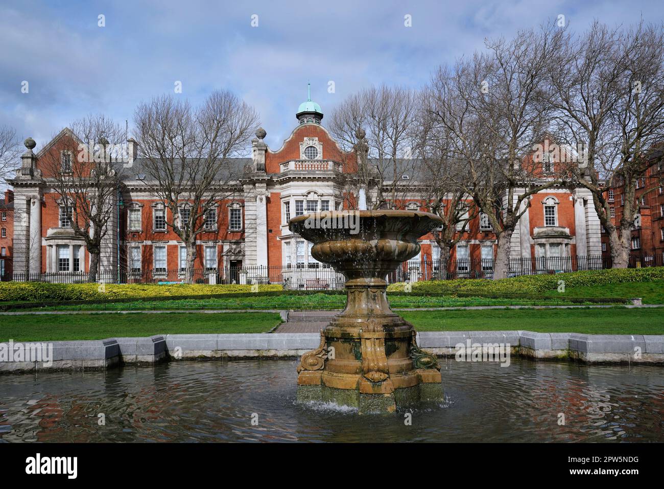 Goblet shaped marble fountain in the middle of an ornamental pond, in St. Patrick's Park, Dublin, next to the cathedral, with Liberties College in the Stock Photo