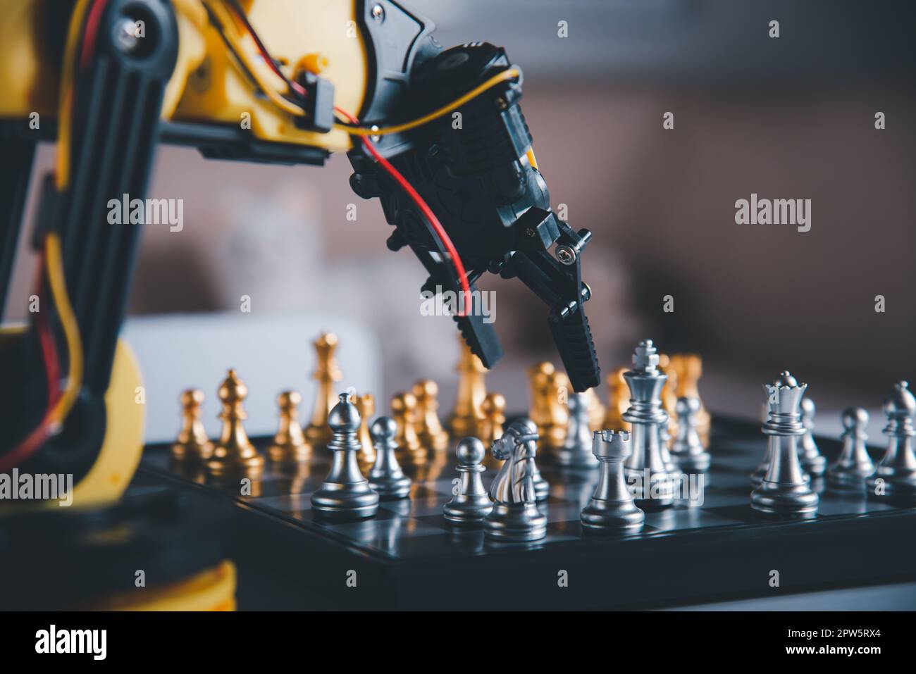 Closeup yellow robot arm playing move chess on chessboard, STEM education E-learning, Technology science robot education concept Stock Photo