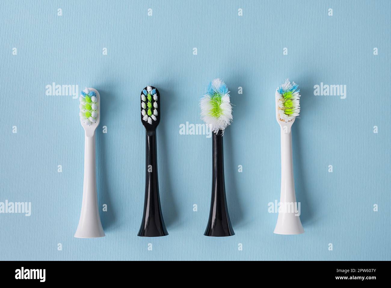 Modern electric toothbrush standing on a blue background, time to