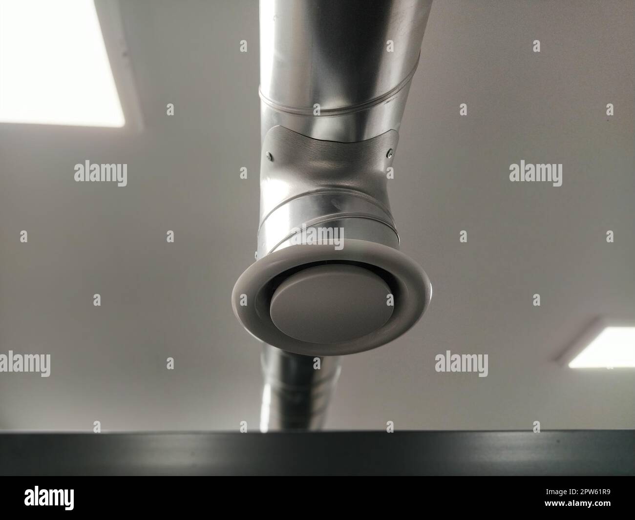 Extractor hood in a public toilet. Round metal pipe with gray air