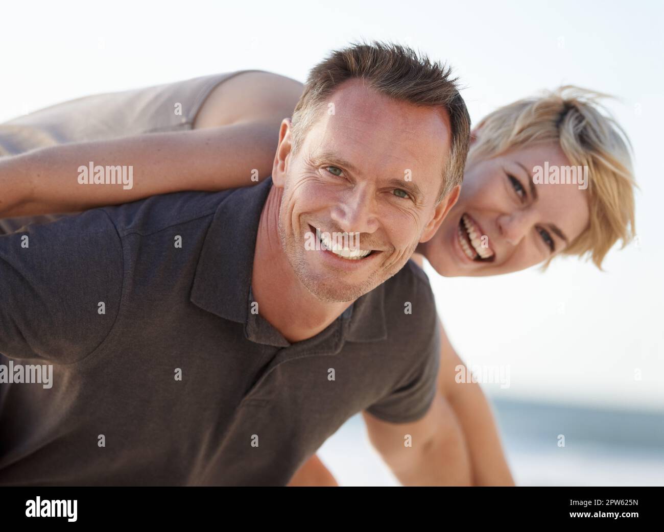 Man giving and adult woman a piggyback ride laughing and having fun in San  Diego, California. Stock Photo