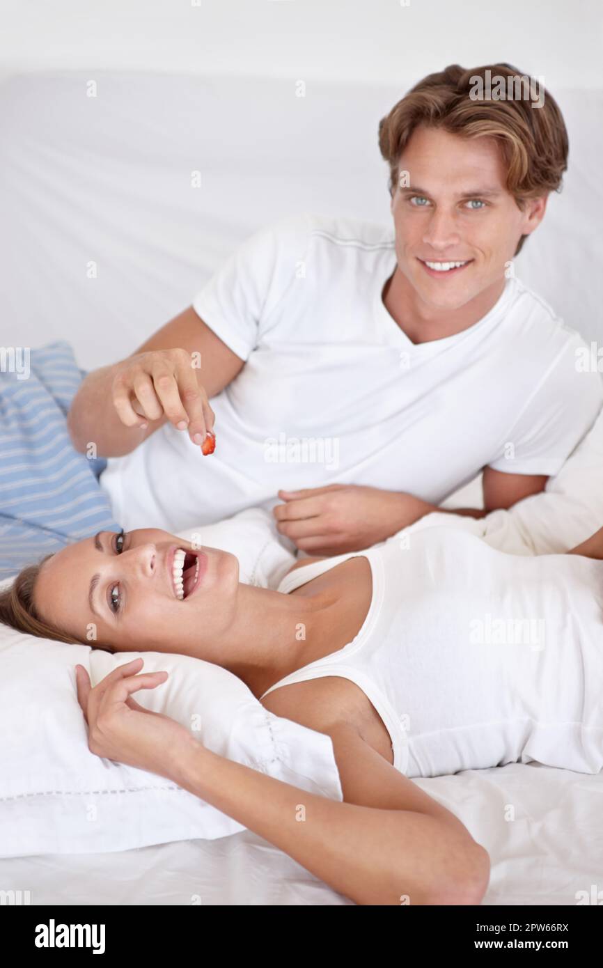 Just one more...A happy young couple eating berries in bed together