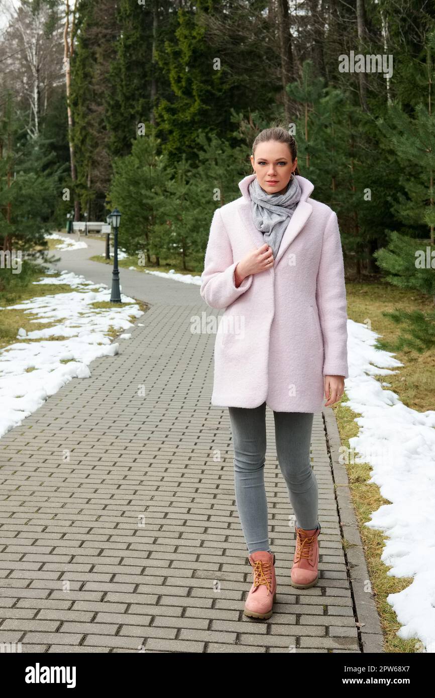 Pretty girl in pink coat walking along pathway in forest Stock Photo