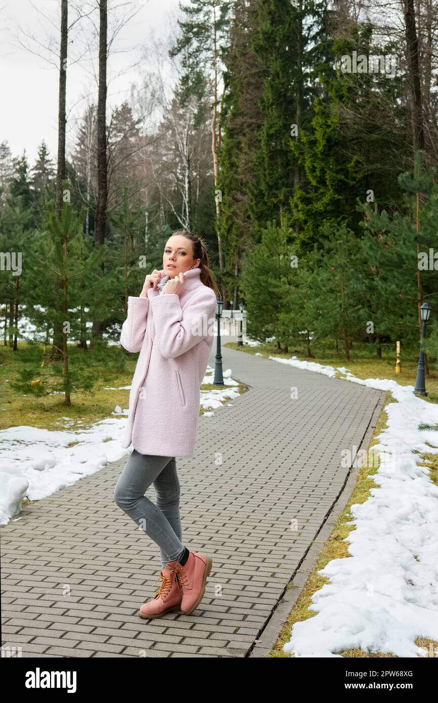 Pretty girl in pink coat walking along pathway in forest Stock Photo