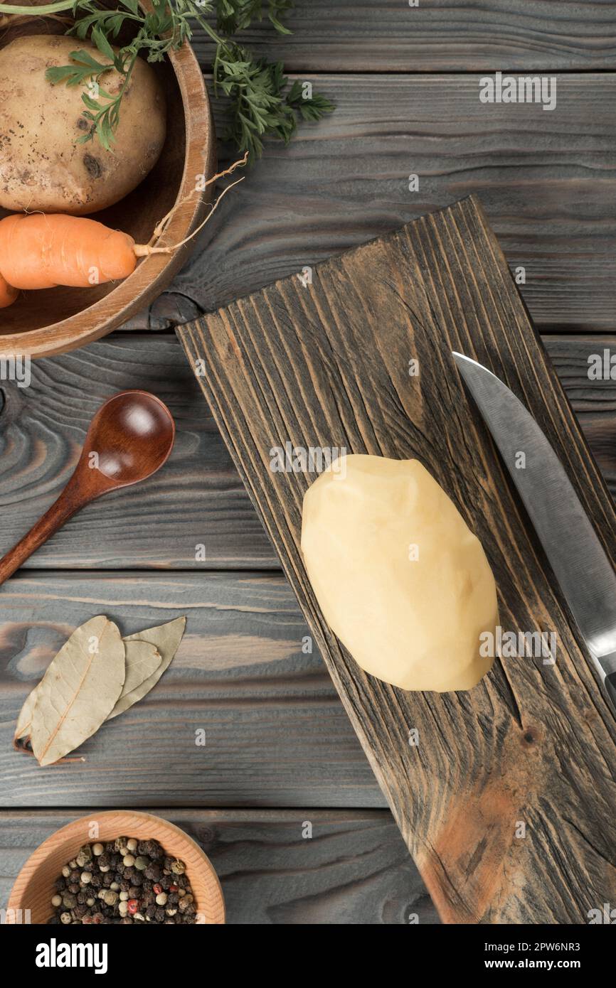 https://c8.alamy.com/comp/2PW6NR3/cutting-raw-yellow-potato-with-knife-on-kitchen-wooden-board-fresh-whole-peeled-potato-traditional-cuisine-flat-lay-view-ripe-vegetables-and-flavo-2PW6NR3.jpg