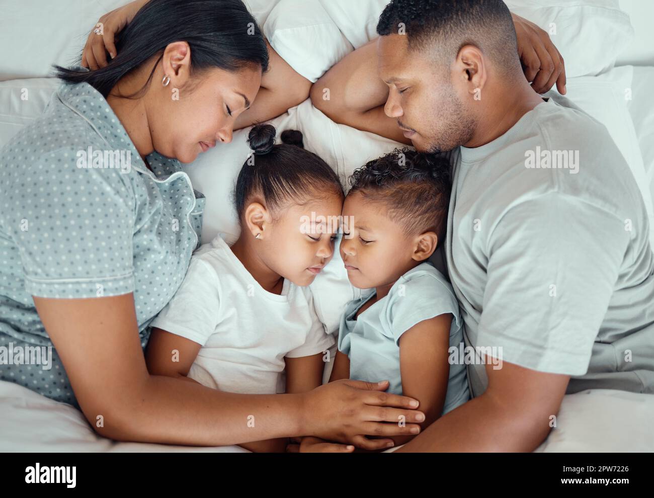 Happy family with two children sleeping together in their parents bed, from above. Loving
