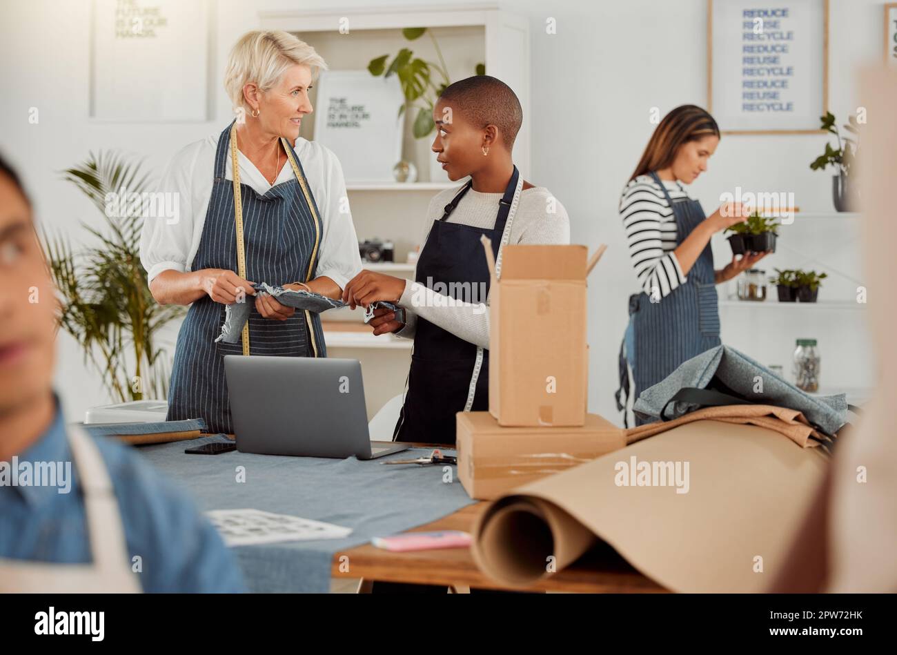 Two clothing designers using a laptop while working with material at ...