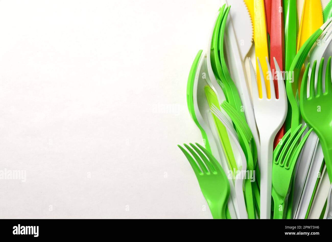 Pile of bright yellow, green and white plastic kitchenware single use