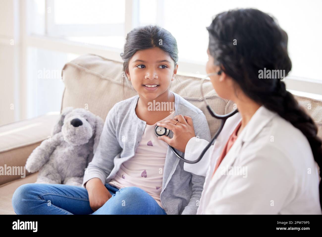 Doctor examining a little girl with stethoscope. Female paediatrician  listening to childs heartbeat during home visit or checkup at clinic.  Caring wom Stock Photo - Alamy