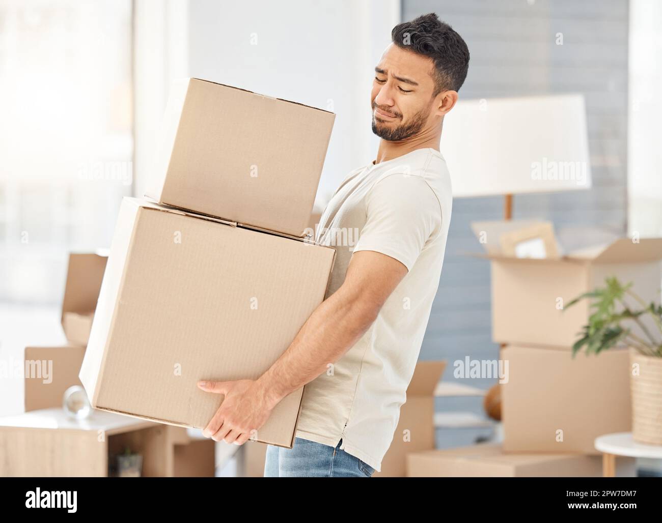 I dont have the muscle for this. a young man carrying heavy boxes while moving house Stock Photo