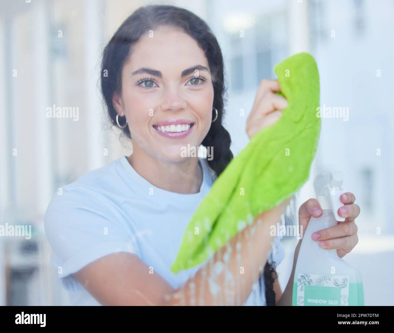 Happy, woman and cleaning home window with cloth and detergent product to polish glass. Spring cleaning, hygiene and clean habit of girl at apartment Stock Photo