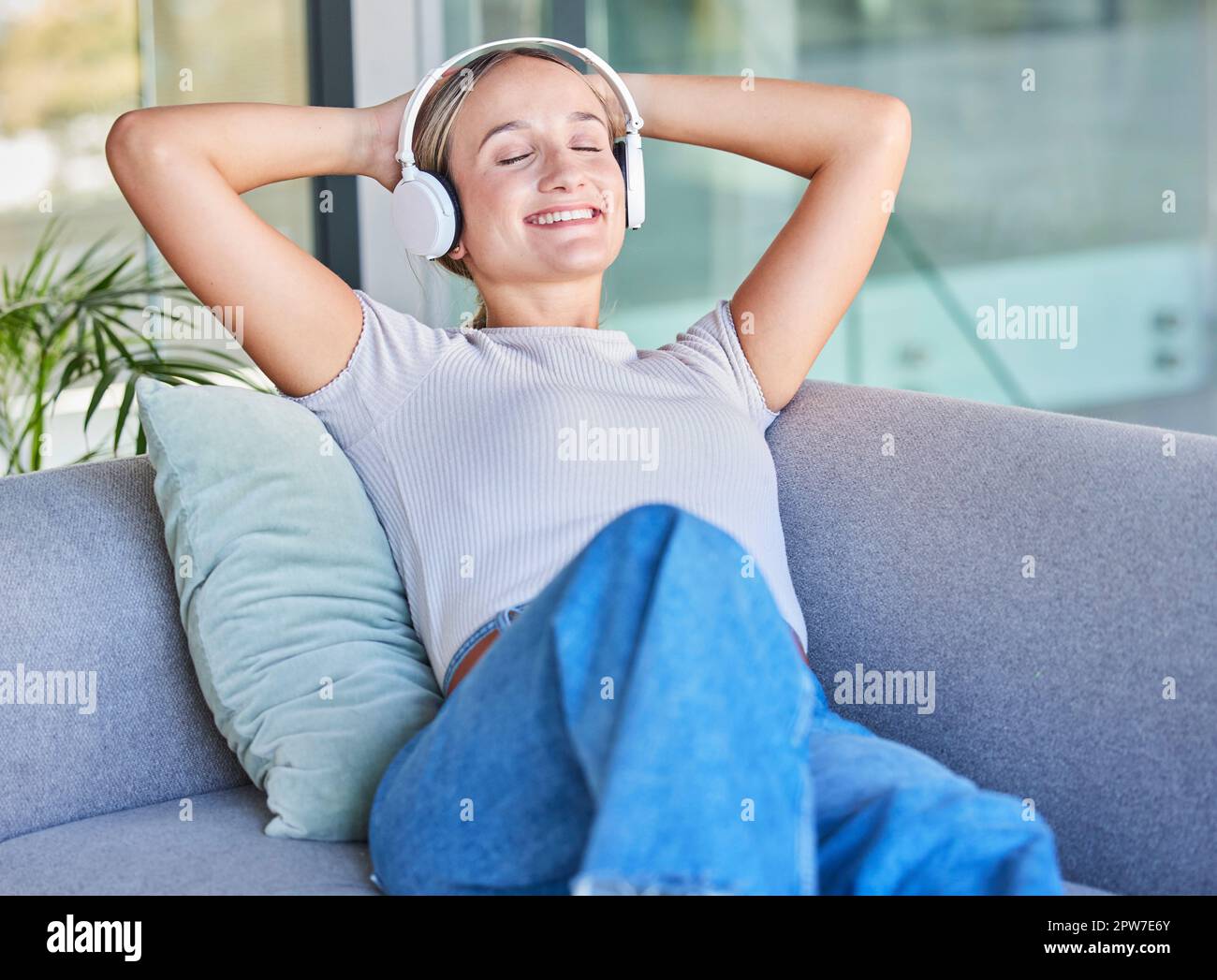 Music, headphones and woman relax on sofa in home living room streaming radio or podcast