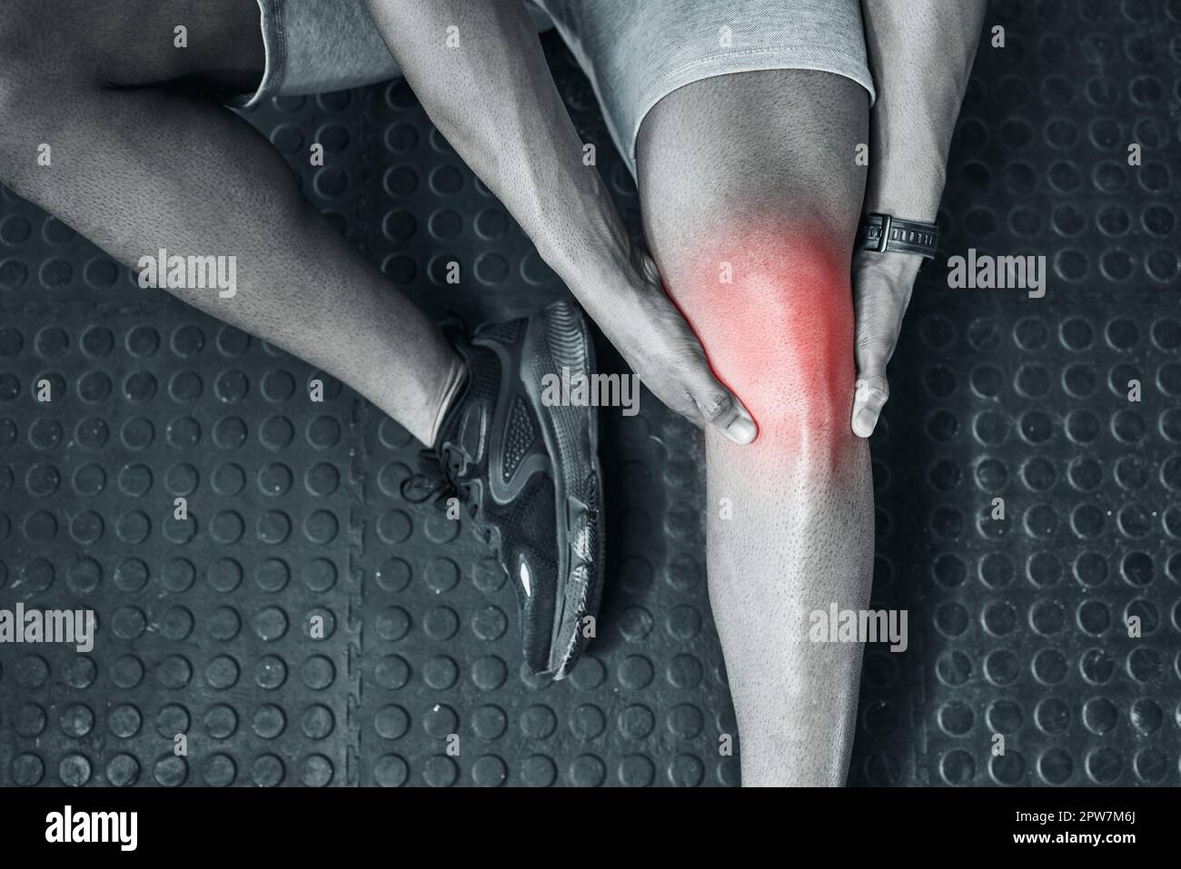 Joint ache is common in the gym. Trainer touching their knee in pain from above. The knee joint