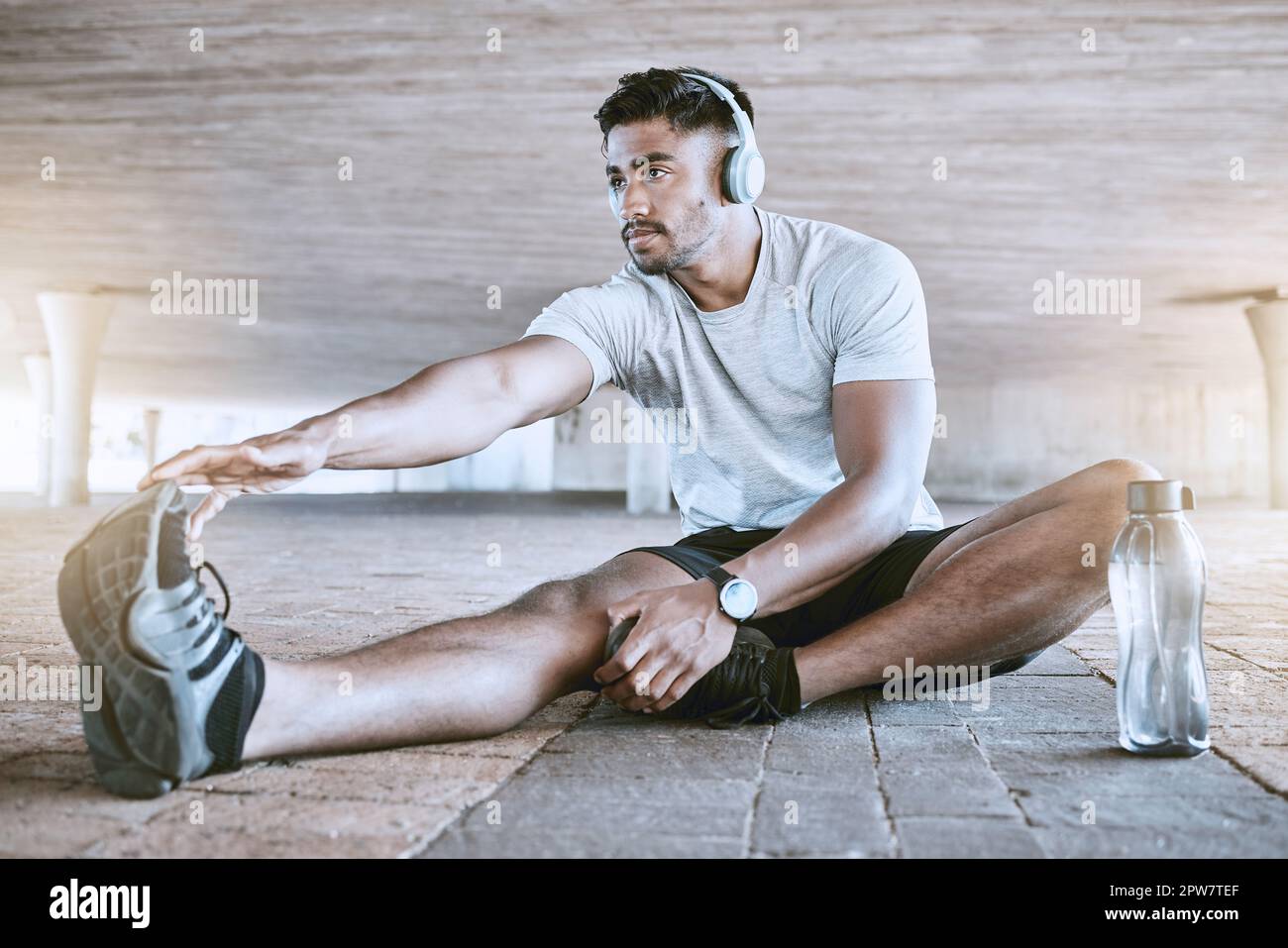 Fit young man stretching his legs while exercising outdoors. Handsome