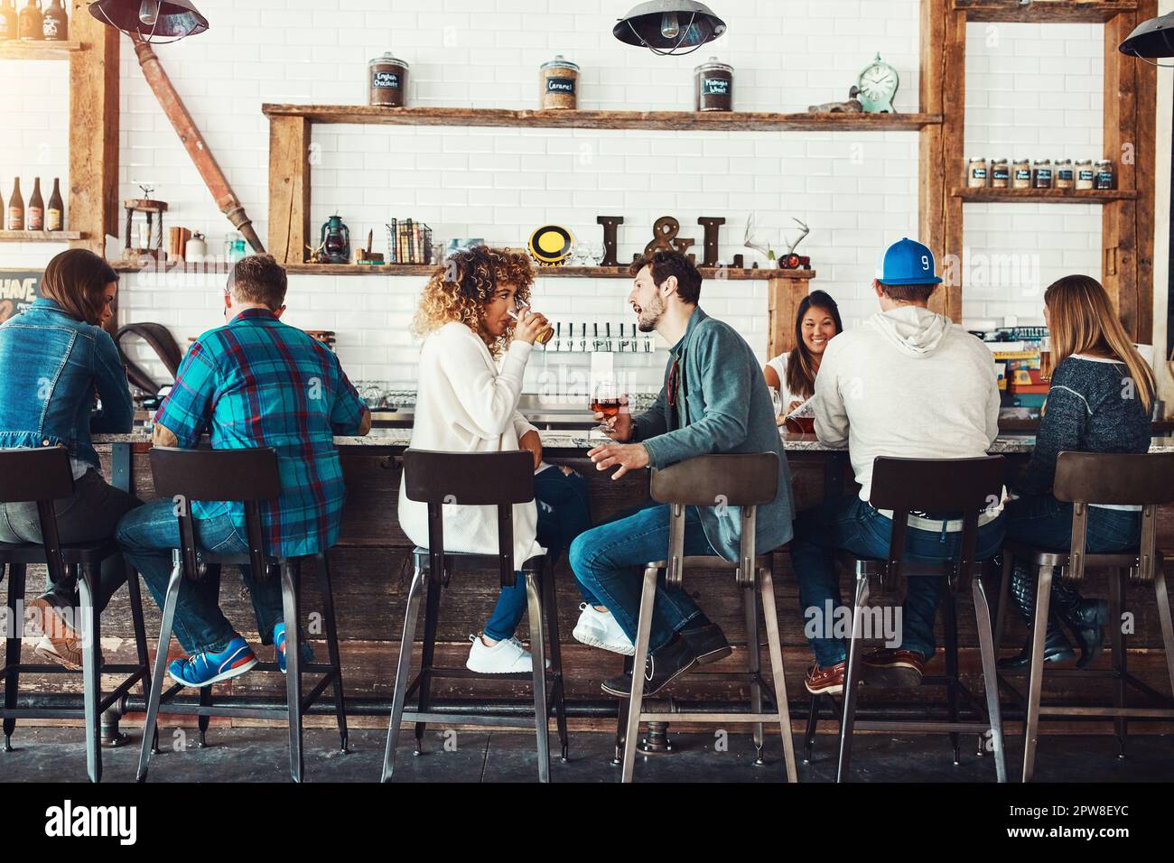Discussing different types of beer. young people enjoying a drink at a bar. Stock Photo