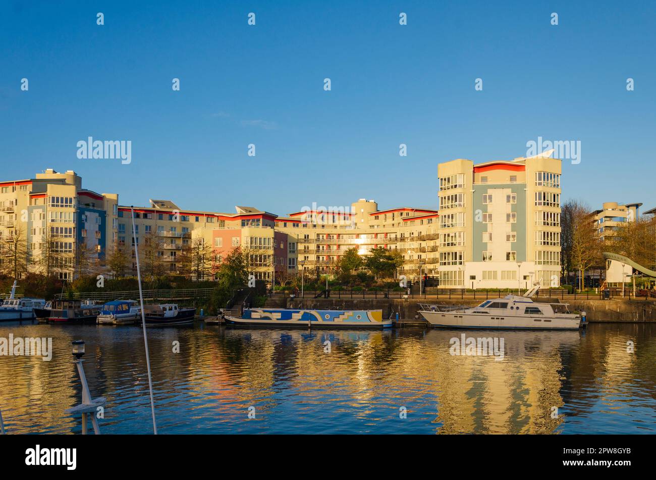 Bristol South west England November 25 2022 - Harbourside Apartment block in Bristol's fashionable Docklands with boats and barge moored and a clear b Stock Photo