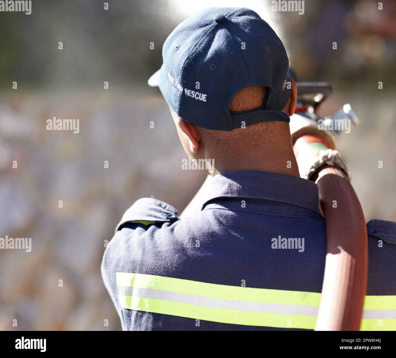 Back, fireman and spray hose with water for emergency with helping, uniform and brave to stop inferno. Firefighter, fire and fearless on mission for Stock Photo