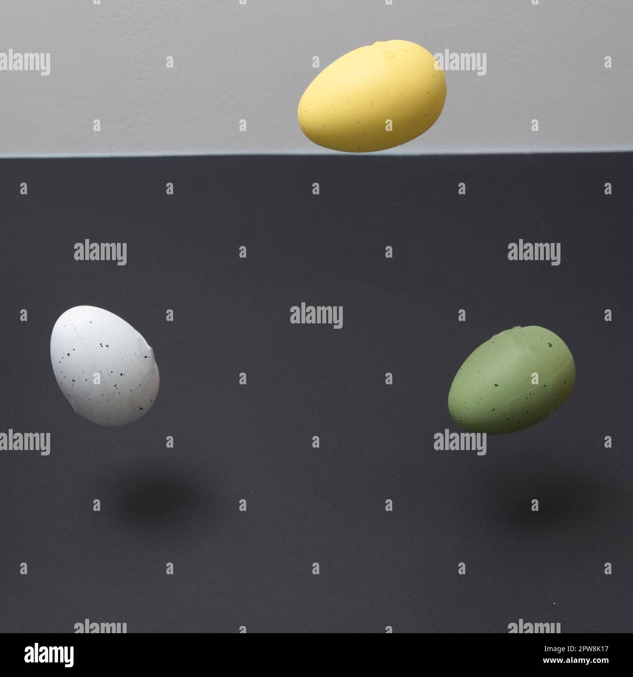 Three colored eggs levitating with copy space on a black and white background. Minimal Easter scene. Stock Photo