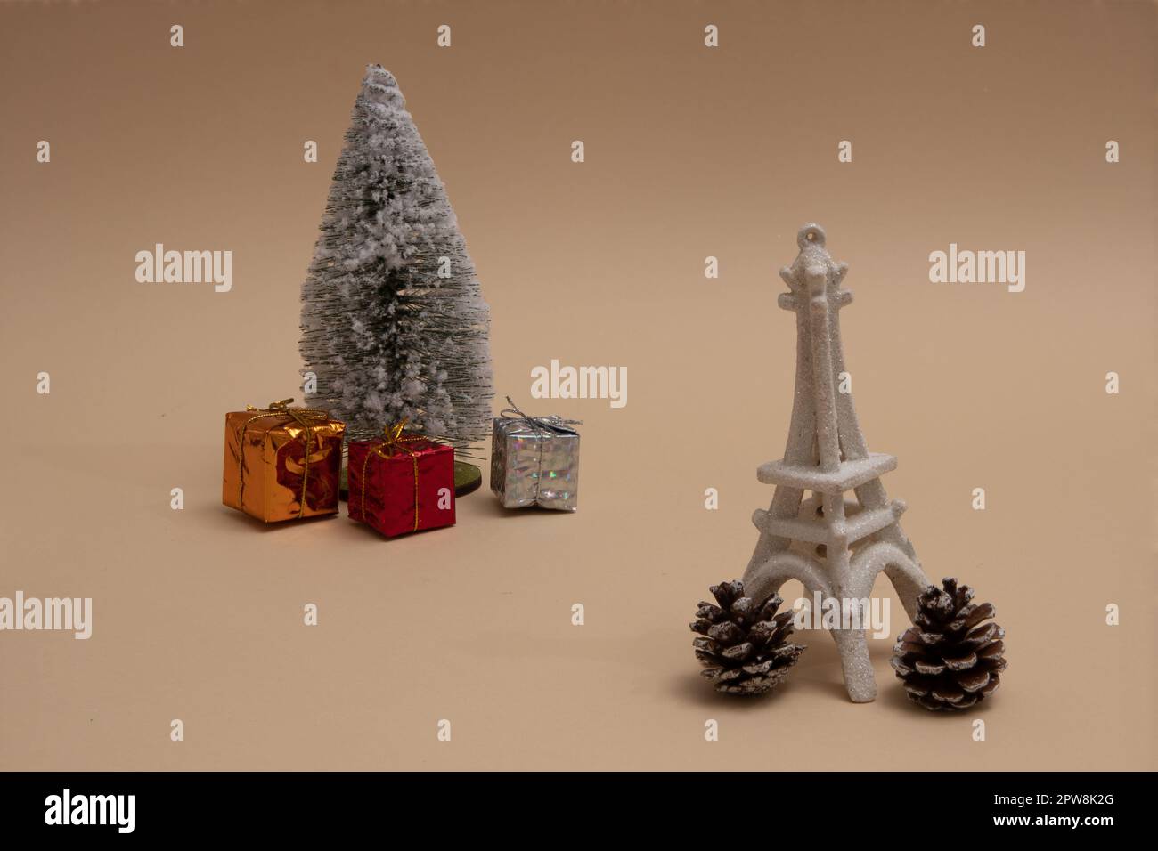 Christmas tree sprinkled with snow, Christmas presents around. Imitation of the Eiffel Tower and cones on beige backgrounds. Aesthetic scene. Stock Photo