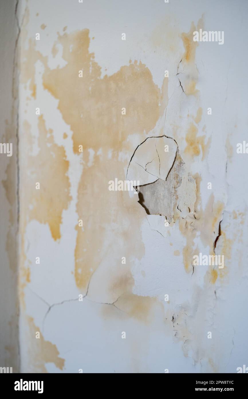 Damaged wall with chipped paint and plaster in traces of leak from faulty water supply at