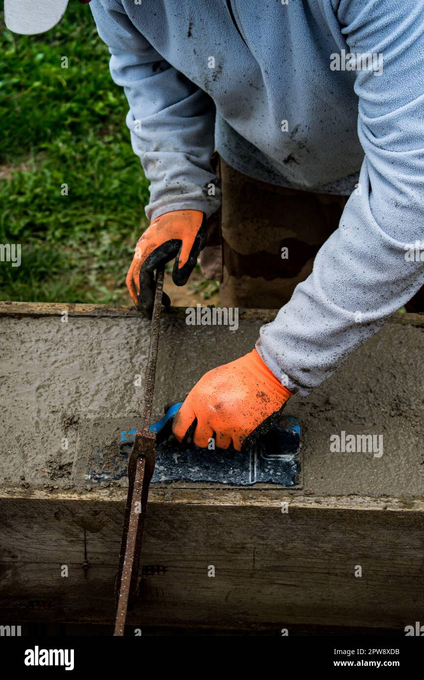 Bricklayer spreading concrete with a trowel and level to build a wall at a construction site Stock Photo