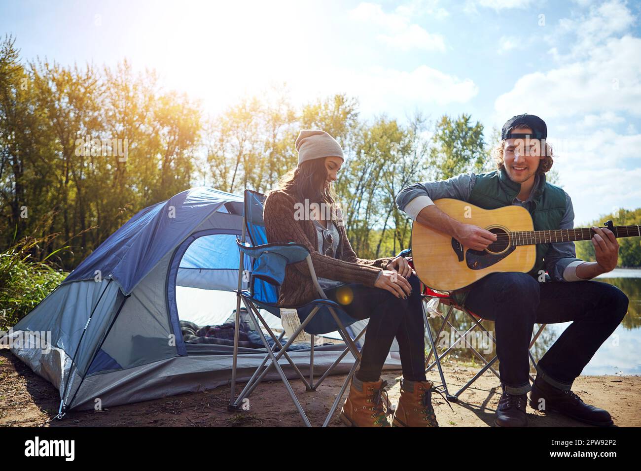 Music is only love looking for words. a young man playing his girlfriend a song on his guitar while out camping. Stock Photo