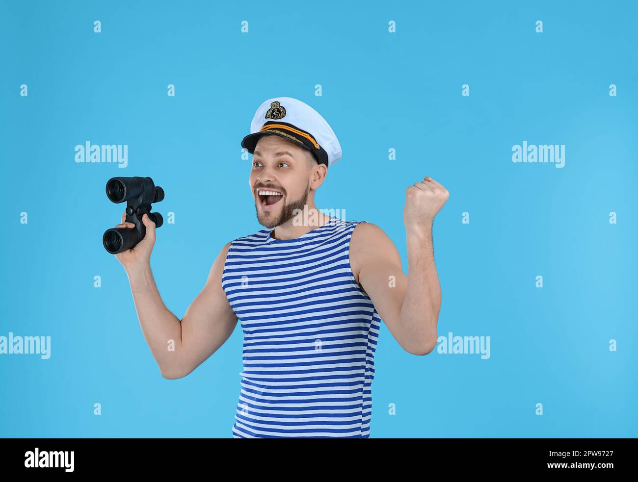 Happy sailor with binoculars on light blue background Stock Photo