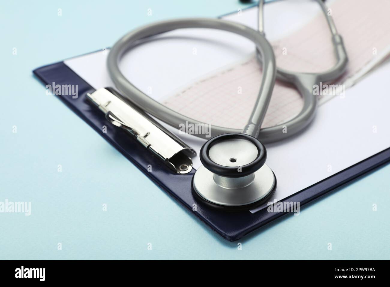 Clipboard with stethoscope and cardiogram on turquoise background, closeup Stock Photo