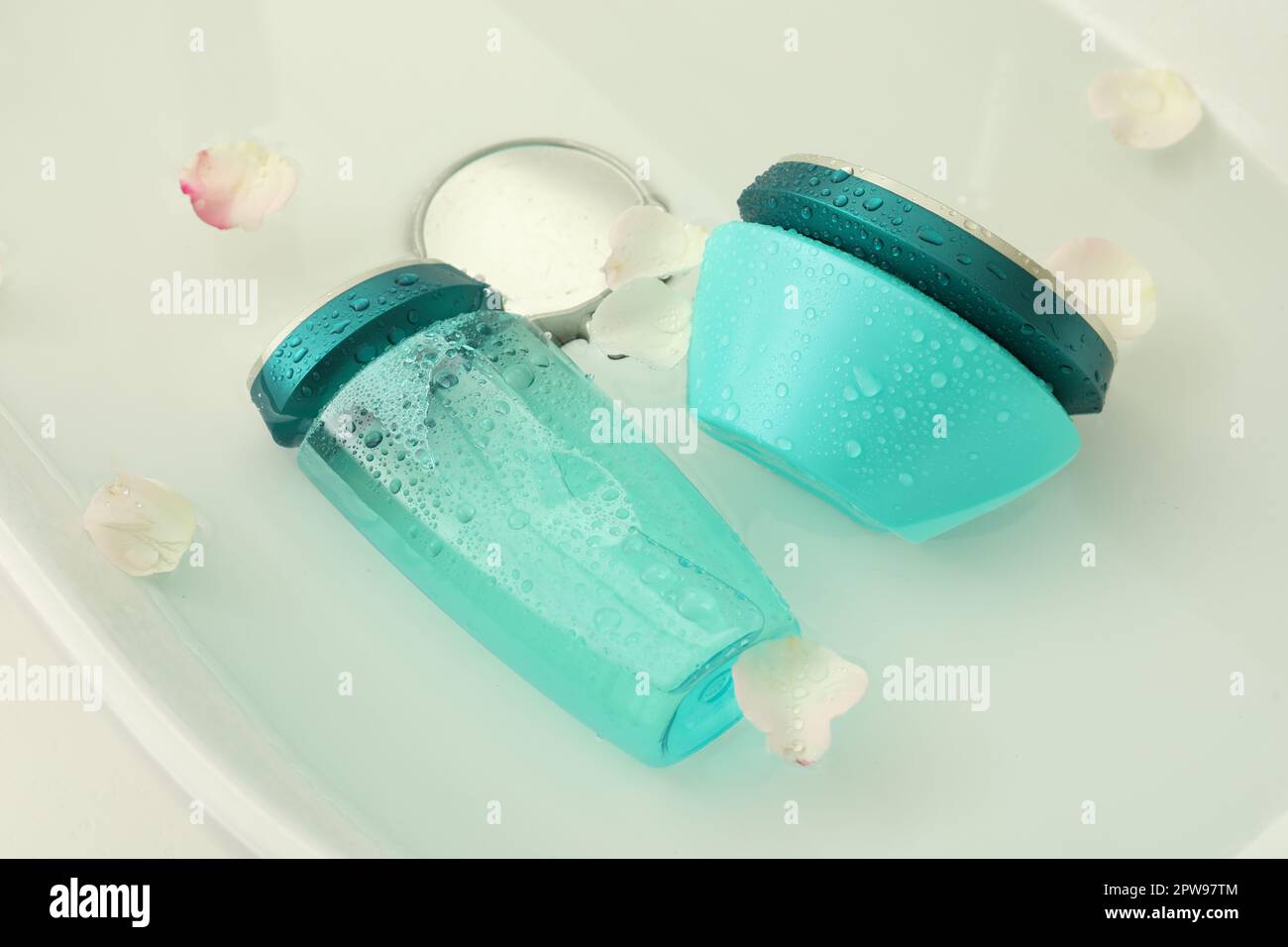 Hair care cosmetic products with flower petals and water in sink Stock