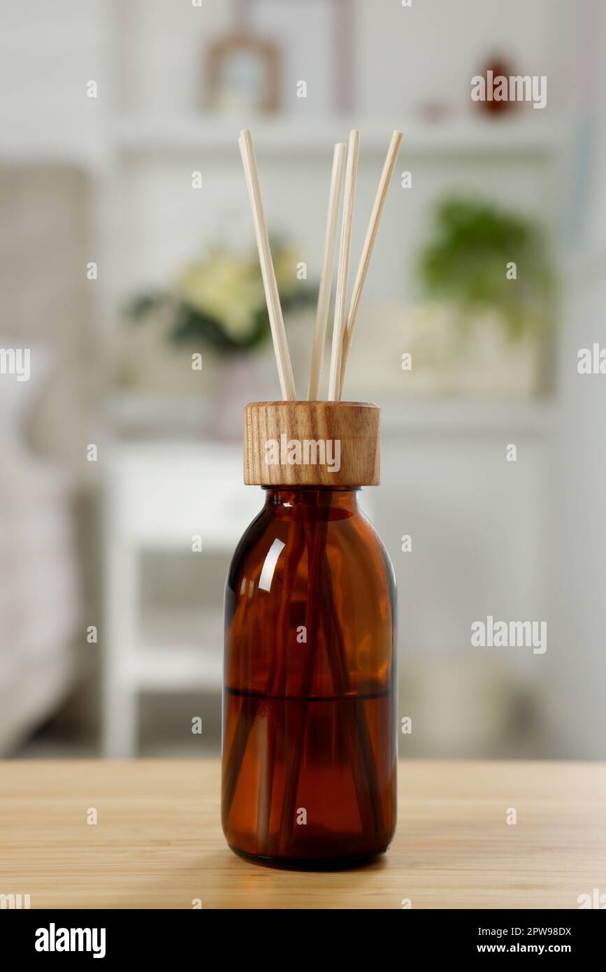Aromatic reed air freshener on wooden table in room Stock Photo