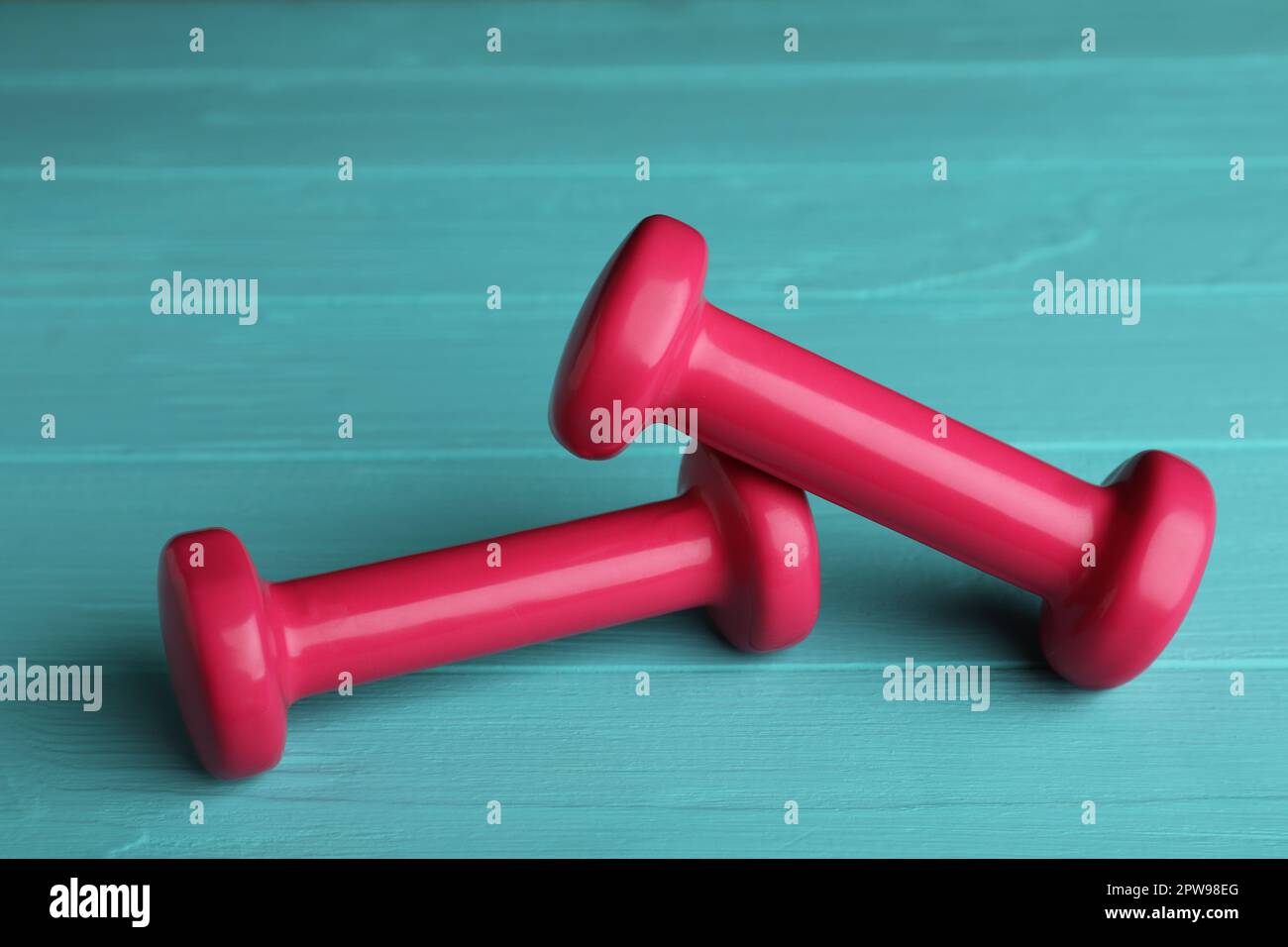 Pink vinyl dumbbells on turquoise wooden table Stock Photo