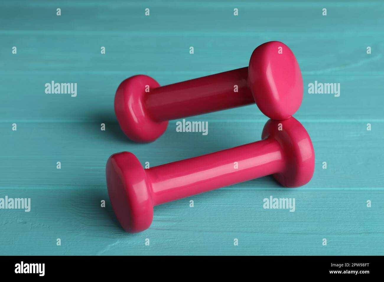 Pink vinyl dumbbells on turquoise wooden table Stock Photo