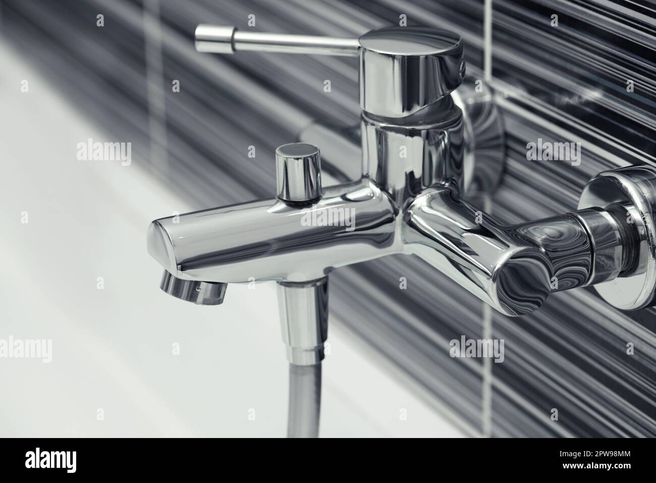 Shiny bath water tap installed on black and white wall Stock Photo Alamy