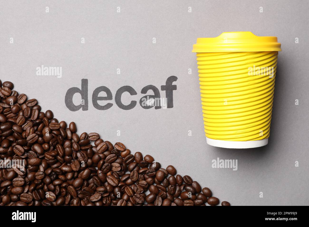 Word Decaf, coffee beans and takeaway paper cup on light grey background, flat lay Stock Photo