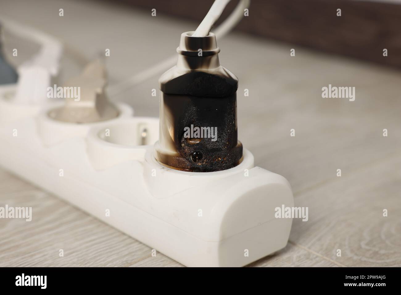 Burnt plug in power strip indoors, closeup. Electrical short circuit