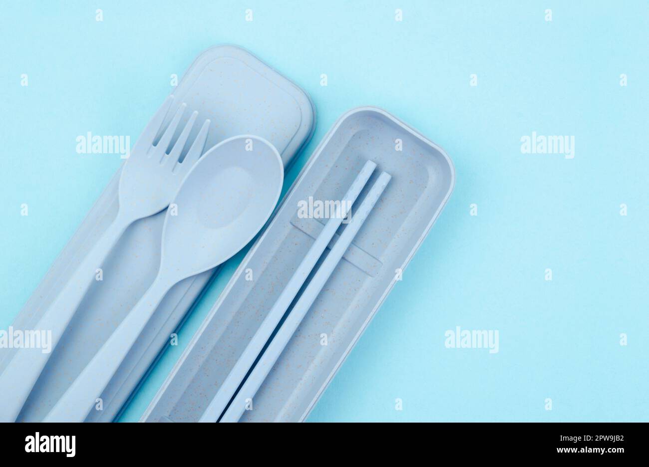 Plastic spoons, forks and chopsticks kit set on blue background. Stock Photo