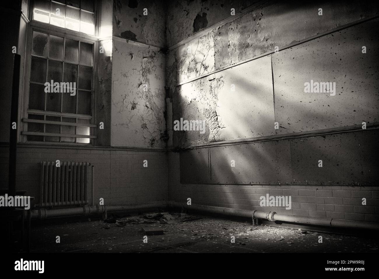 Light finds a way through the boarded windows into a hall of the derelict Easington Colliery School, now demolished. Stock Photo