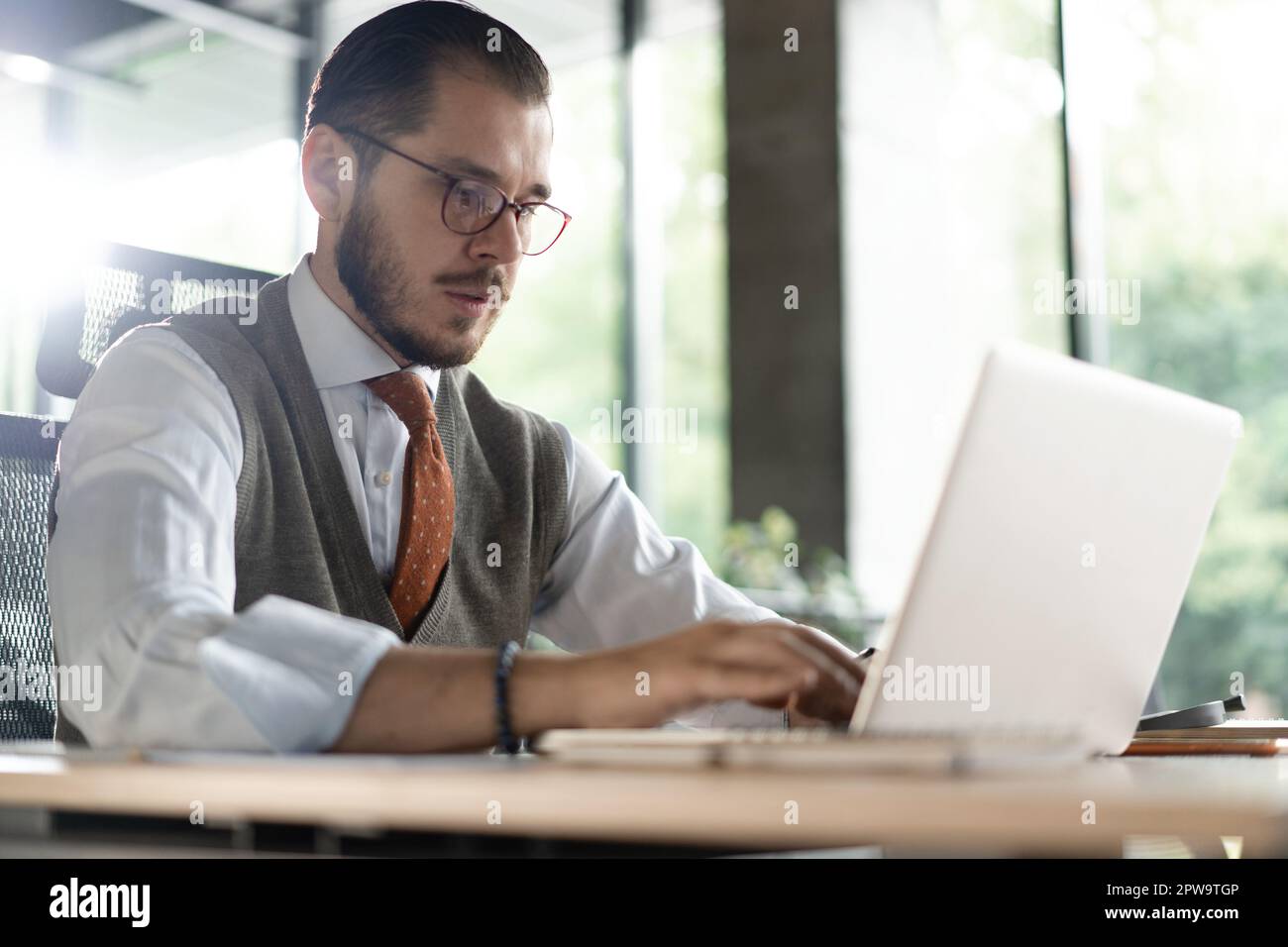 Modern Office Businessman Working on Computer. Portrait of Successful Middle-aged IT Software Engineer Working on a Laptop at his Desk Stock Photo